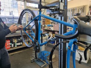 A mechanic is shown adjusting the cable tension on a bicycle in for a Single Speed Service at Abbotsford Cycles