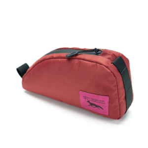 A Swift Industries Moxie Top Tube Bag is shown in a reddish orange material with a black zipper and a pink logo