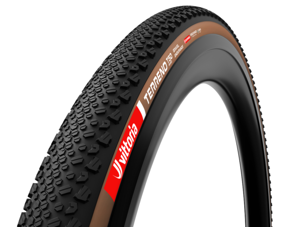 A black with brown sidewall Vittoria Terreno T50 Mixed Gravel Endurance tyre is shown in a render, fitted to a black carbon bicycle rim